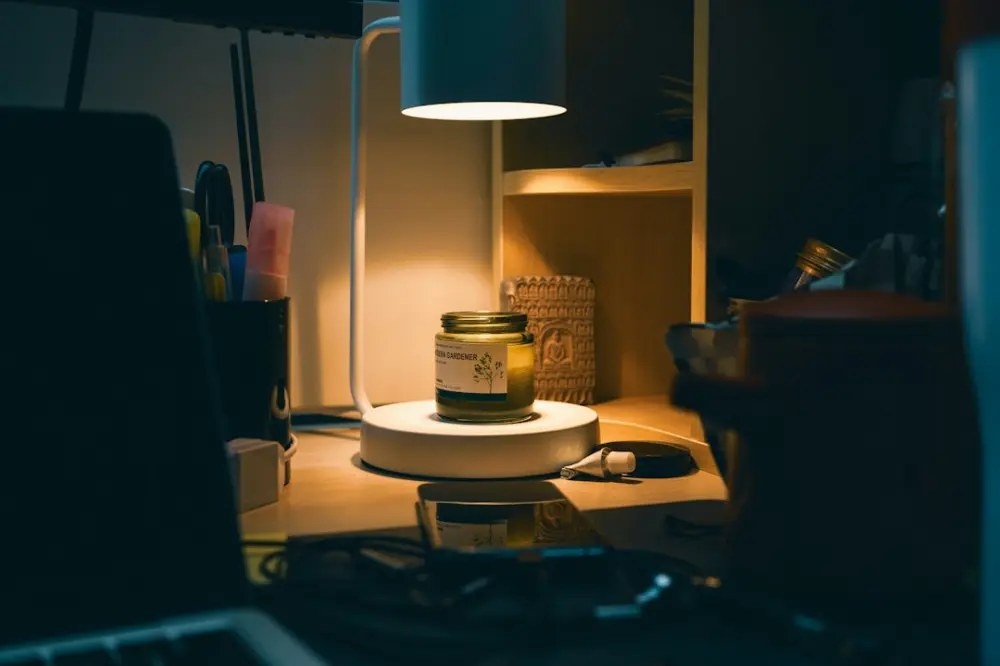 Desk lamp illuminates candle jar on a dimly lit workspace, illustrating personal clarity